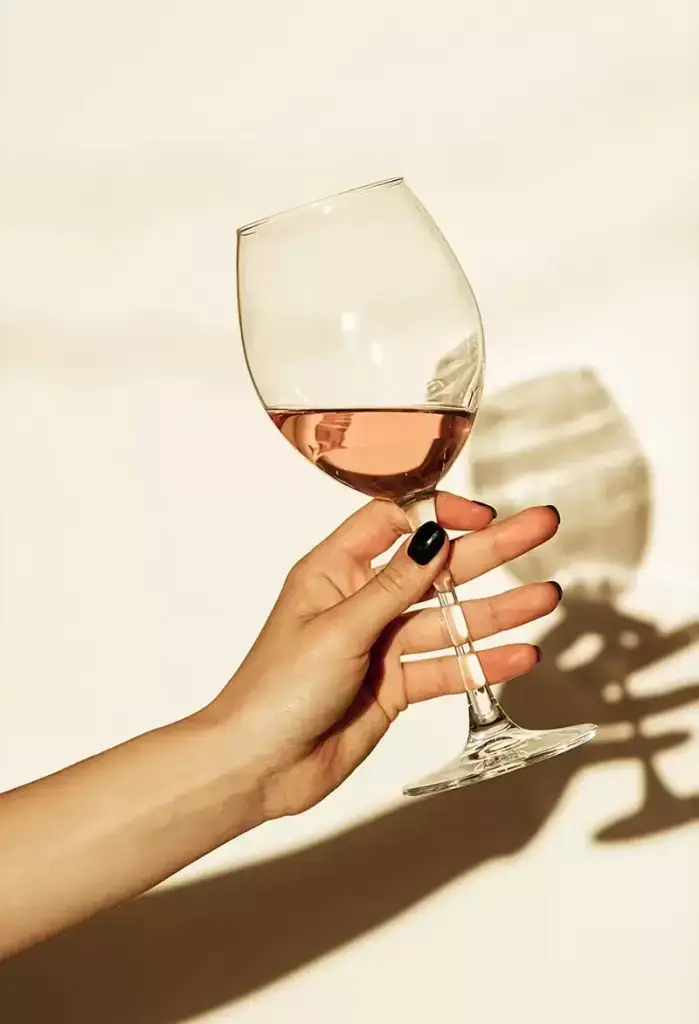 Main tenant un verre de vin rosé